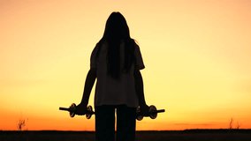 Girl exercising with dumbbells in park at sunset. Beautiful young woman exercising outdoors. Motivation to exercise for an active life. Girl doing strength training, dumbbell in nature. Fitness nature - Powered by Shutterstock - Get 15% off with code: PIKWIZARD15