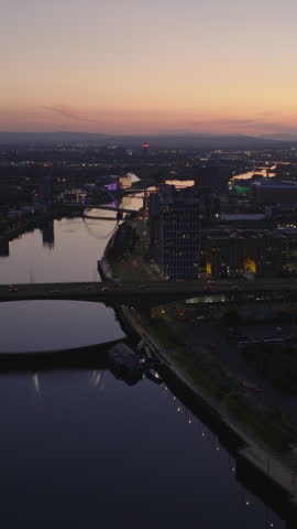 Vertical establishing shot of Glasgow skyline at night. Aerial view of urban metropolis in Scotland, United Kingdom