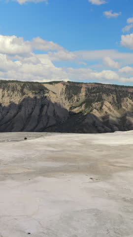 Majestic mountain landscape at Yellowstone National Park showcases natures splendor, featuring a vibrant blue sky with fluffy clouds, capturing the wonder of outdoors and inviting exploration 