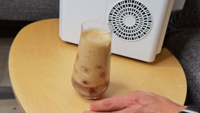 Carbonated cola overflowing with rich foam into an ice-filled glass. Crisp indoor shot on wood surface. Ideal for beverage ads, product promos, and food content.
