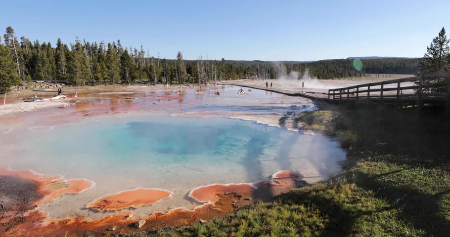 A beautiful blue lake with a red and orange rim. The water is calm and the sky is clear