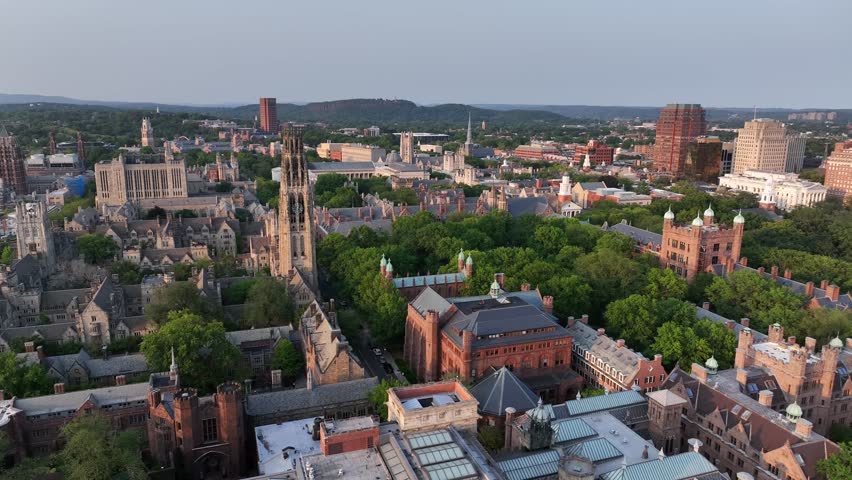 Historic town of New Haven in Connecticut, USA. golden sunset time in summer. Descend drone wide shot. Gothic Yale university and tower buildings in center. Downtown complex in distance. Brick gothic.