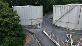 Petroleum and fuel storage in suburb of American town. Trees in summer. Pipelines connecting tanks. Aerial view. - Powered by Shutterstock - Get 15% off with code: PIKWIZARD15