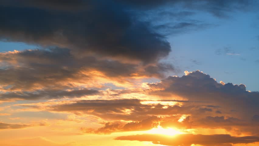 A sunset timelapse captures golden light breaking through dark clouds, painting the sky in fiery orange and soft blue tones, reflecting the shifting beauty of evening weather in nature’s cycle.
