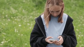 Young blonde hiker standing in blooming green meadow, browsing smartphone while enjoying nature's scenic landscape and wireless connectivity - Powered by Shutterstock - Get 15% off with code: PIKWIZARD15