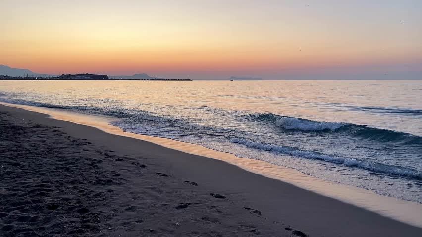 Evening view of Rethymno city beach in Crete, Greece. Tranquil shoreline after sunset with soft waves and calm atmosphere, Mediterranean seaside.