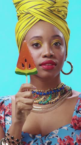 A Vibrant Woman Holding a Watermelon Lollipop While Dressed in Colorful Fashion Ensemble