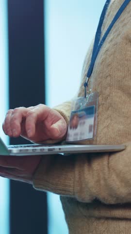 A person is utilizing a laptop while wearing an ID badge in a modern office workspace