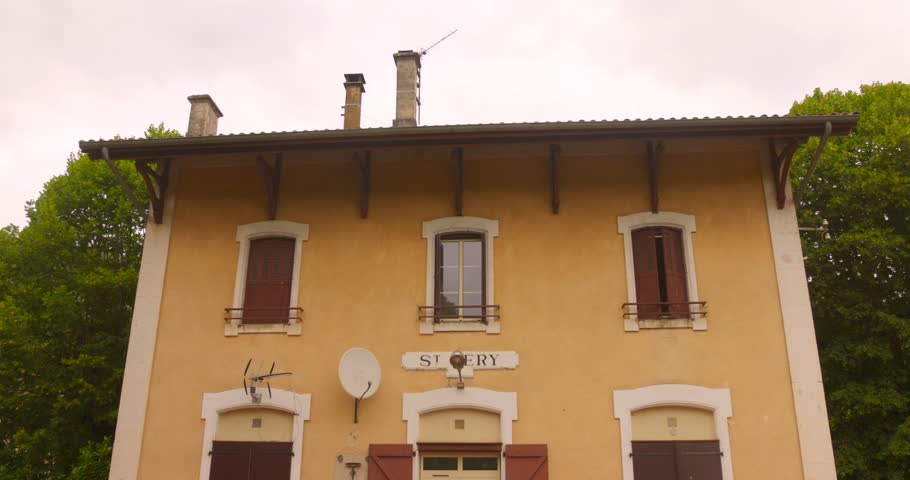 Shot of a former railway station with overgrowing nature in Saint-Géry, France on a cloudy day. 4k.