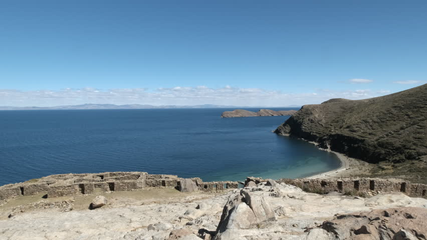 A stunning pan shot showcasing the historic Isla del Sol and its enigmatic Chincana Labyrinth on Lake Titicaca, Bolivia. The ancient Inca ruins and the serene beauty of this sacred South American site