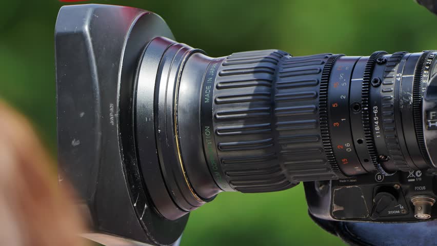 Professional telephoto zoom lens with lens hood attached, capturing a sporting event