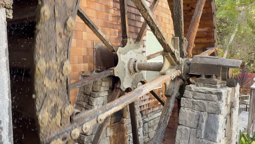 Rotating water mill. Old wooden water mill. Mill wheel rotating under stream of water. Waterwheel turning water in old mill