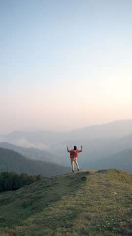 A man trekking through the wilderness near Bhrigu Lake in Manali, Himachal Pradesh, India, raises his strong arm toward the mountaintop.