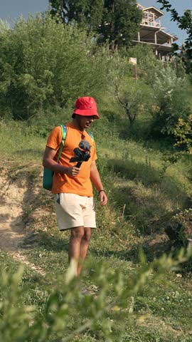 A happy young man taking a selfie with a camera on a stick in Manali, Himachal Pradesh, India, capturing adventure travel moments—ideal for vlogging or lifestyle content.