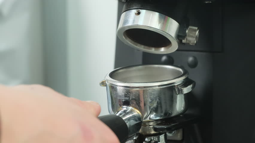 Grinder finely grinds coffee beans to reveal future flavour of beverage. Preparation of coffee-based drinks using modern equipment
