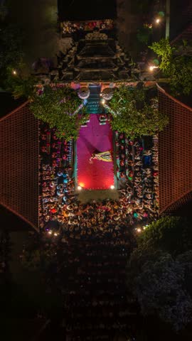 Aerial timelapse of traditional Balinese dance performance at night in Ubud, Indonesia, with illuminated stage, audience, and temple architecture.