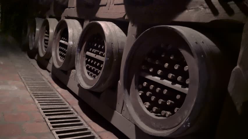 wine bottles and wine barrels in the wine cellar of a winery