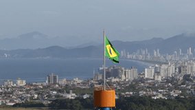 Brazilian flag waving with Itajaí city and Balneário Camboriú skyline in the distant background. - Powered by Shutterstock - Get 15% off with code: PIKWIZARD15