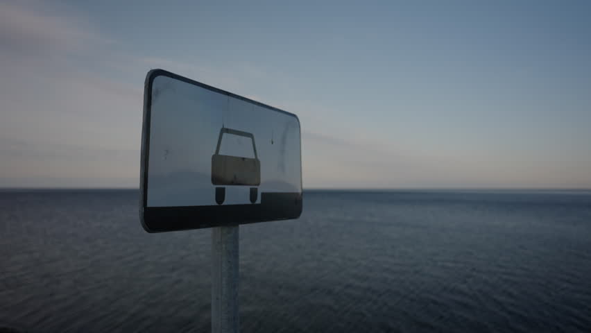 Metal parking sign standing by tranquil lake waters, reflecting serene Russian landscape with soft sky and quiet shoreline background, no people, nobody, slow motion. Concept of vacation in Russia.