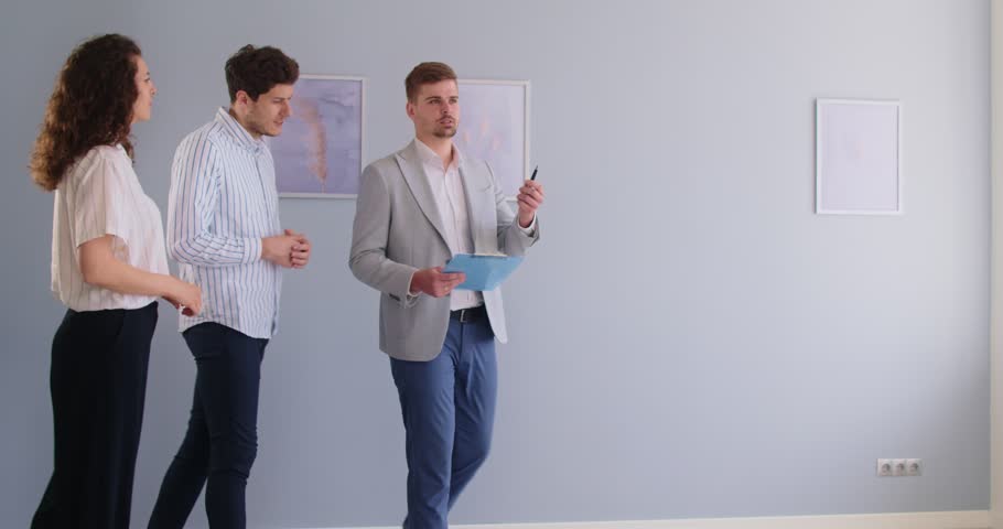 House tour by real estate agent for young couple before lease, rent or purchase new home apartments. Salesman showing room to woman and man, realtor and clients meeting, walking to inspect property