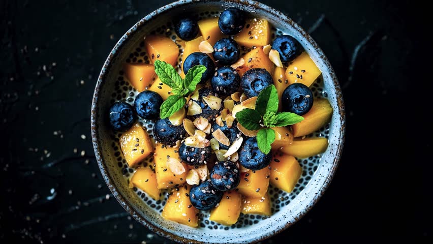 A vibrant bowl of mango cubes, blueberries, and chia seeds for a fresh and healthy treat.
