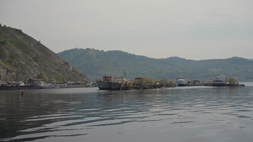 Sunken and weathered ships create captivating scene in waters of lake Baikal, near port Baikal, with shoreline and hills providing dramatic backdrop. Concept of vacation and travel in Russia.