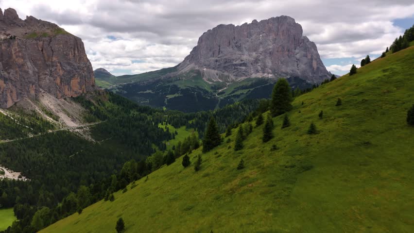 Cinematic drone flight over the treetops toward the majestic Sassolungo mountain, Dolomites, Italy