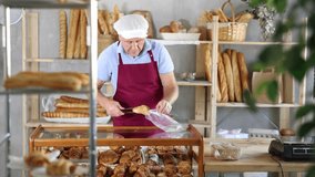 Elderly man seller puts croissants in bag in bakery store - Powered by Shutterstock - Get 15% off with code: PIKWIZARD15