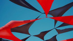 abstract view of red and black triangle shaped cloth decoration waving by wind on blue sky background. summer sea camp or beach club decoration, vibrant colors - Powered by Shutterstock - Get 15% off with code: PIKWIZARD15