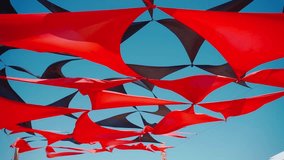 abstract view of red and black triangle shaped cloth decoration waving by wind on blue sky background. summer sea camp or beach club decoration, vibrant colors - Powered by Shutterstock - Get 15% off with code: PIKWIZARD15