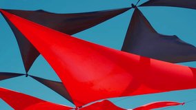 abstract view of red and black triangle shaped cloth decoration waving by wind on blue sky background. summer sea camp or beach club decoration, vibrant colors - Powered by Shutterstock - Get 15% off with code: PIKWIZARD15