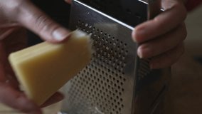 Grating hard cheese on metal kitchen grater. - Powered by Shutterstock - Get 15% off with code: PIKWIZARD15