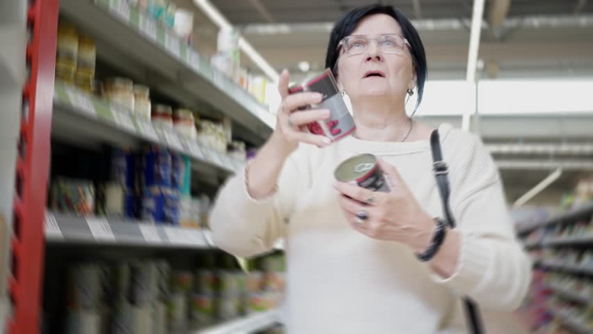 An elderly woman is engaged in the act of shopping for groceries at a local store