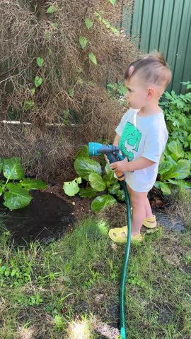 Toddler enjoying water play with garden hose summertime