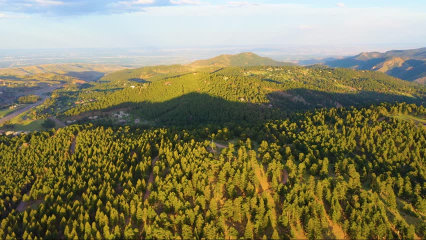 Sweeping cinematic aerial of Colorado Rockies at golden hour, golden light over rugged ridges, shimmering alpine lakes, and lush green meadows, high-quality 4K drone footage perfect for nature lovers.