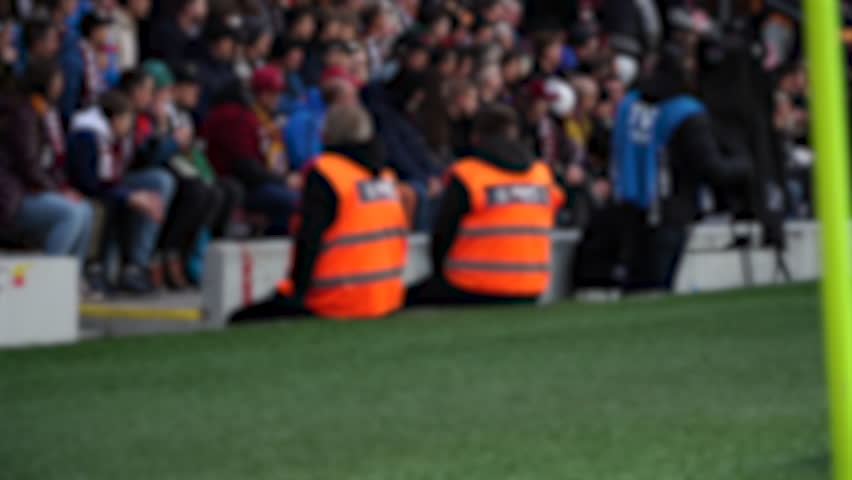 Blur Football stadium security, stewards in yellow vests, security staff watching crowd, stadium guards during match, soccer security on duty, safety control at sports event,