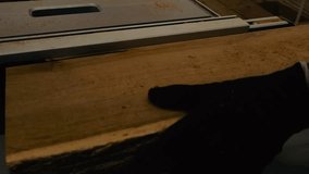 Close up view of a black gloved hand pushing a oak timber slab on a table saw indoors at a workshop with wood chips and sawdust flying behind it in slow motion. Wood grain and texture visible clearly. - Powered by Shutterstock - Get 15% off with code: PIKWIZARD15