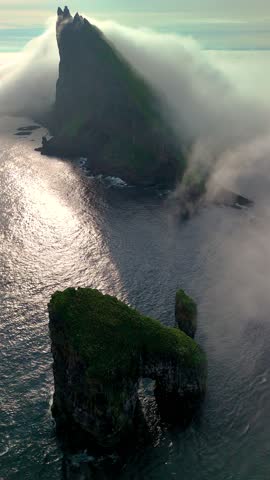 Experience the stunning beauty of Drangarnir Cliffs, where dramatic rock formations emerge from the misty ocean. Located in the picturesque Faroe Islands, nature showcases its artistry.