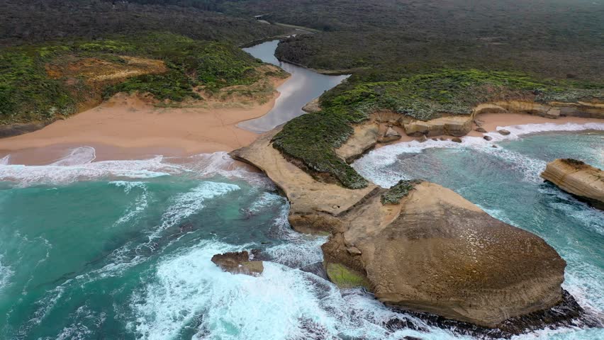 A scenic drone view of the Great Ocean Road in Victoria, Australia, specifically highlighting a coastal area with a river meeting the ocean