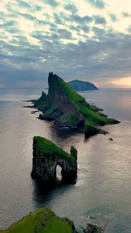 Experience the dramatic beauty of Drangarnir cliff in the Faroe Islands, where steep rock formations rise sharply from the serene ocean, showcasing natures raw power and elegance at twilight.