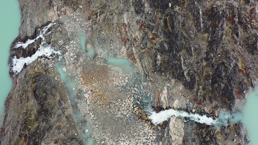 A top-down view of icy blue water winding through glacier-carved valleys in Kangerlussuaq Fjord, Greenland