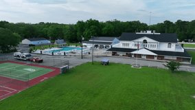Aerial view of campsite area with American flag. Grass field, swimming pool and tennis field in America, New Jersey. Approaching shot. - Powered by Shutterstock - Get 15% off with code: PIKWIZARD15