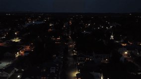 Nightscape in small American town with driving car on Main Street. Aerial wide shot. Sleeping families in house and homes. Illuminated church towers. Peaceful housing area. - Powered by Shutterstock - Get 15% off with code: PIKWIZARD15