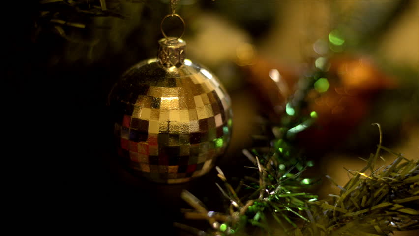 A golden bauble decoration hanging on a Christmas tree.