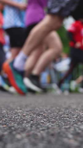 Marathon runners crowd, sportsmen participants start running the half-marathon in the city streets, crowd of sportswomen joggers in motion, group athletes outdoor training competition in summer day