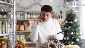 Guy calls on mobile phone and holds a grocery basket. Man calls and wishes his friends a happy New year. Buying snacks for a holiday party - Powered by Shutterstock - Get 15% off with code: PIKWIZARD15