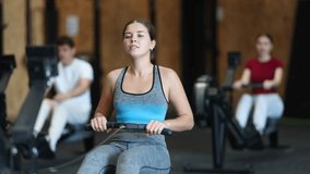 Athletic woman in top and leggings training intensively on rowing machine in  gym. European adheres to a healthy lifestyle and creates her figure in functional training - Powered by Shutterstock - Get 15% off with code: PIKWIZARD15