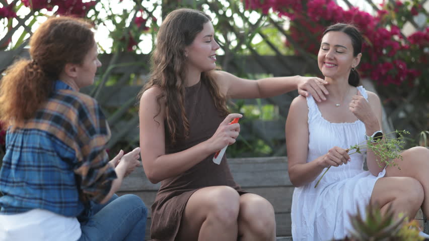 Young and two adult women applying mosquito repellent in cottage garden. High quality 4k footage