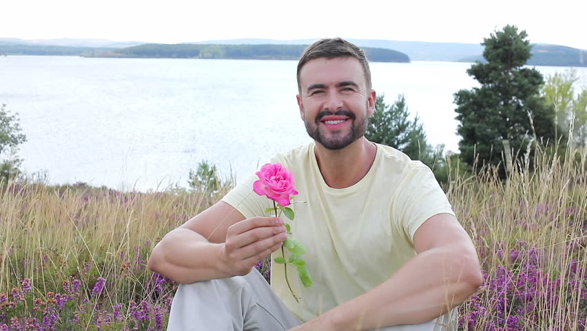 Man smelling a flower in stunning natural setting 