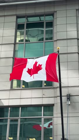 DOLLY SLOW MOTION SHOT - The Canadian flag waving in the breeze with downtown Toronto in the background, Ontario, Canada.